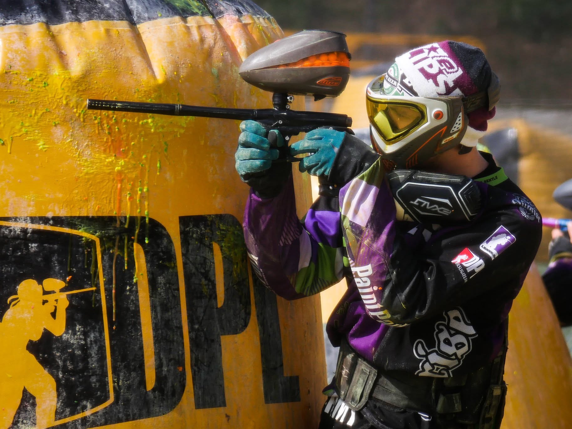 Paintball Turnierspieler mit Maske und Markierer an einer SupAir-Deckung
